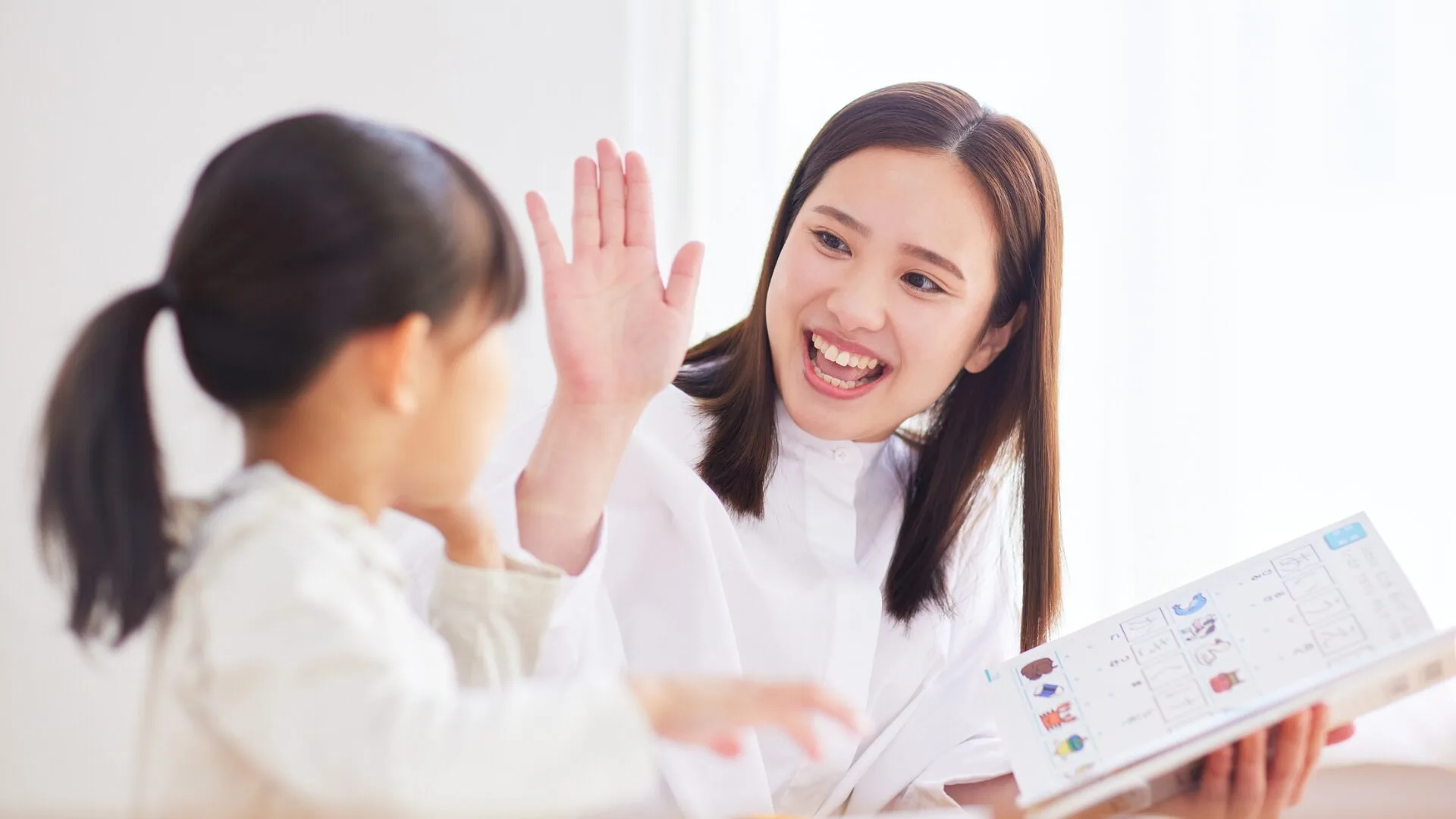 笑顔で女の子とハイタッチをする家庭教師