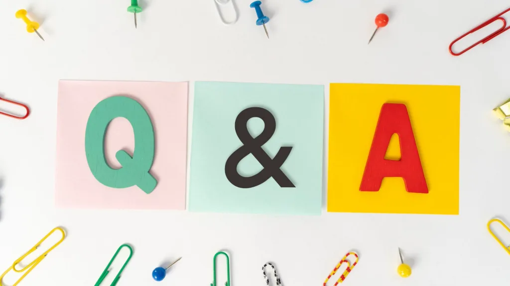 「Q&A」の文字ブロックが置かれたカラフルな付箋と、その周りに散らばるクリップや画鋲