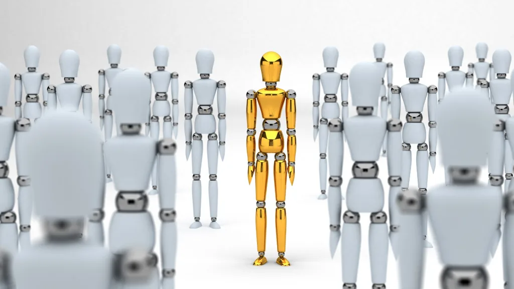 たくさんの白い人型ロボットの中に、一体だけ金色のロボットが立っている